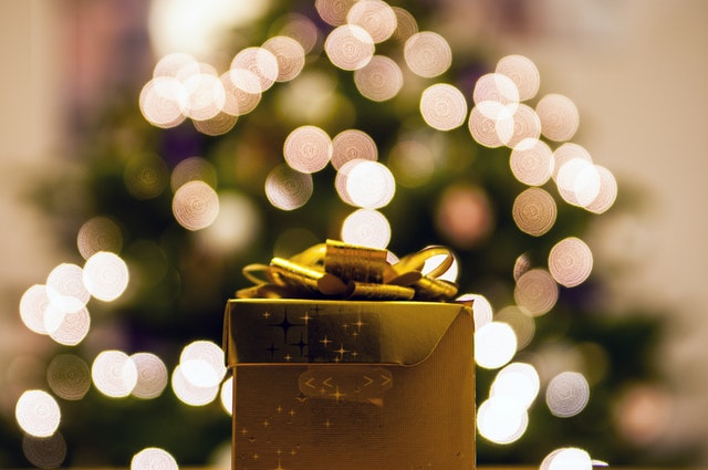 a present wrapped in gold under holiday lights 