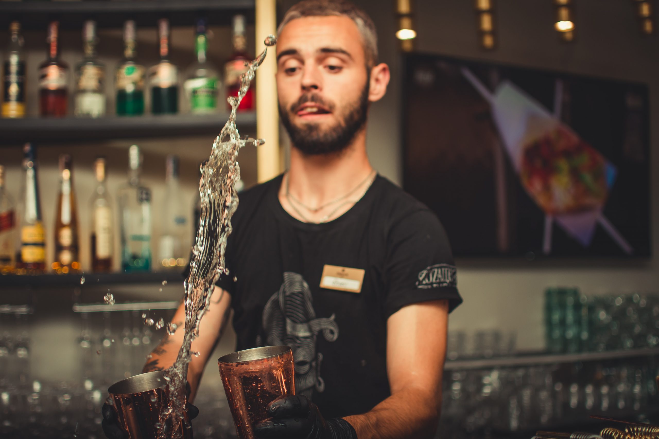 Hearing Loss Is More Prevalent in Service Workers Bartender mixing up a drink with the drink flying in the air to the next cup