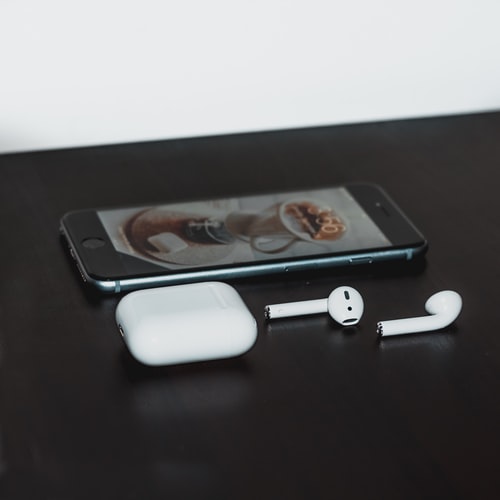 A pair of earbuds next to a smartphone.