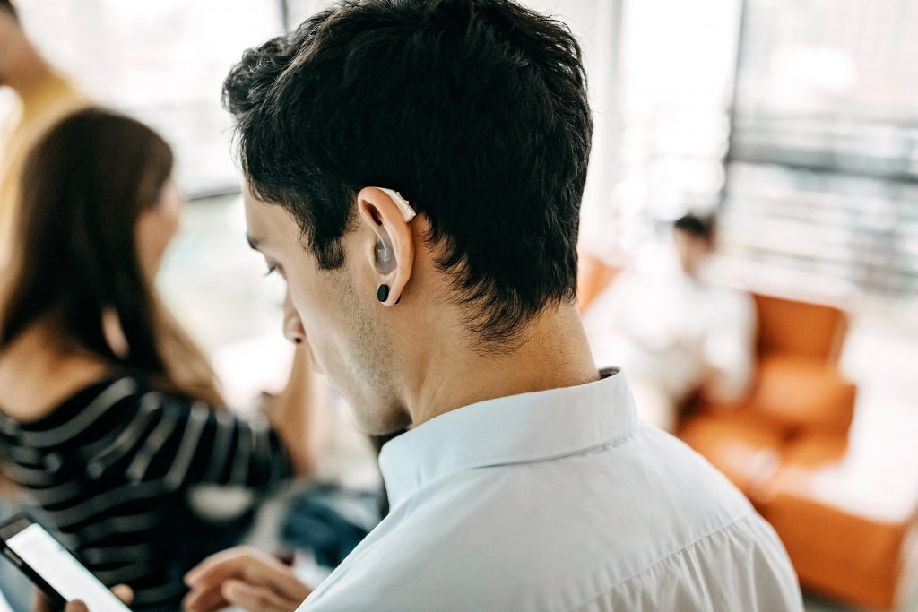 Friendly Teamwork Man with a hearing aid looks at his smart phone.