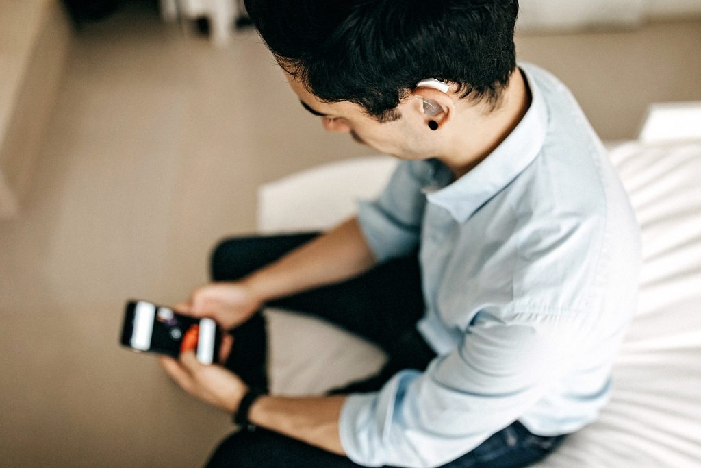businessman-hearing aid-batteries Businessman with hearing aid checking cellphone.